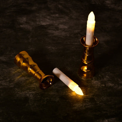 One gold-based LED candle stands upright while another lies on its side with the candle removed.