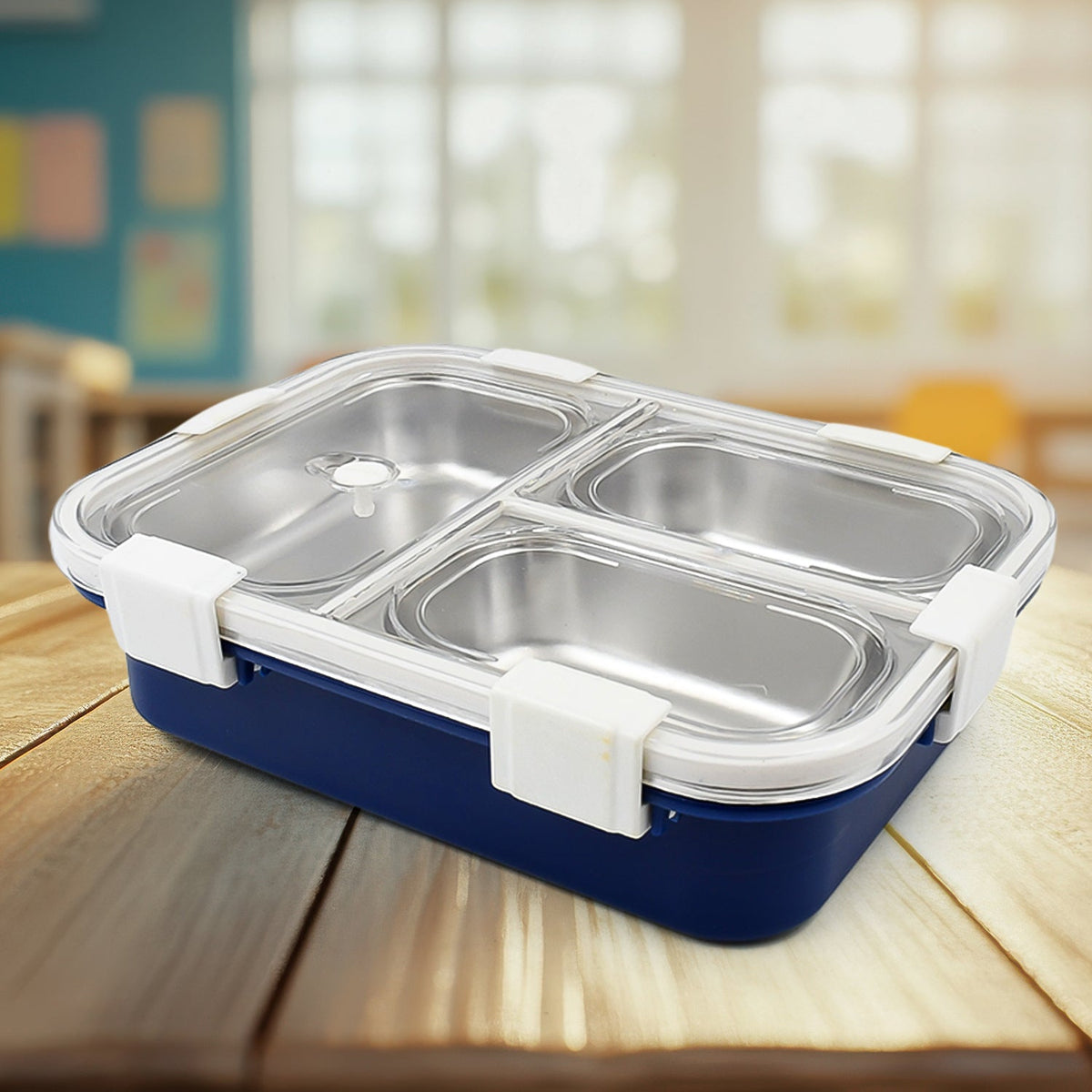 A blue lunch box with three stainless steel compartments and white clasps, surrounded by various snacks.