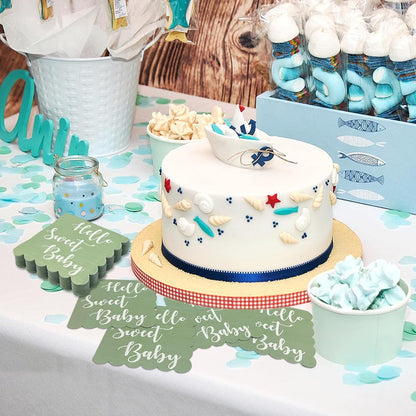 Mint green scalloped napkins on a table with a white cake decorated with a boat and blue accents, and other party treats.