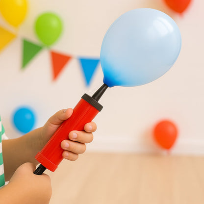 Hands hold a red and black balloon pump inflating a light blue balloon, with party decorations in the background.