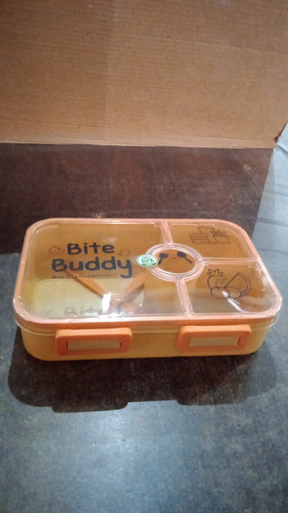 Closed yellow 4-compartment lunch box with clear lid and orange accents on a dark surface.
