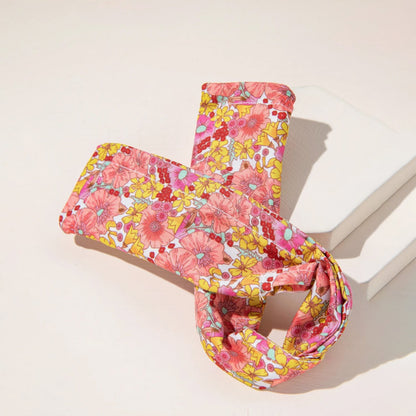 Pink and yellow floral hair bun maker folded over white blocks on a light pink surface.