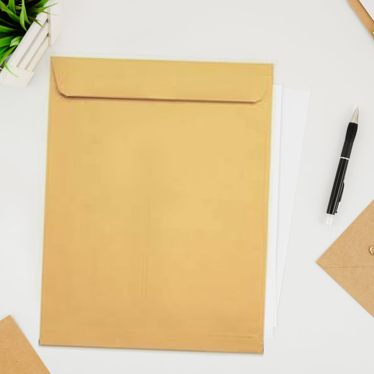 A large brown kraft envelope with white papers inside, next to a pen and a small plant on a white desk.