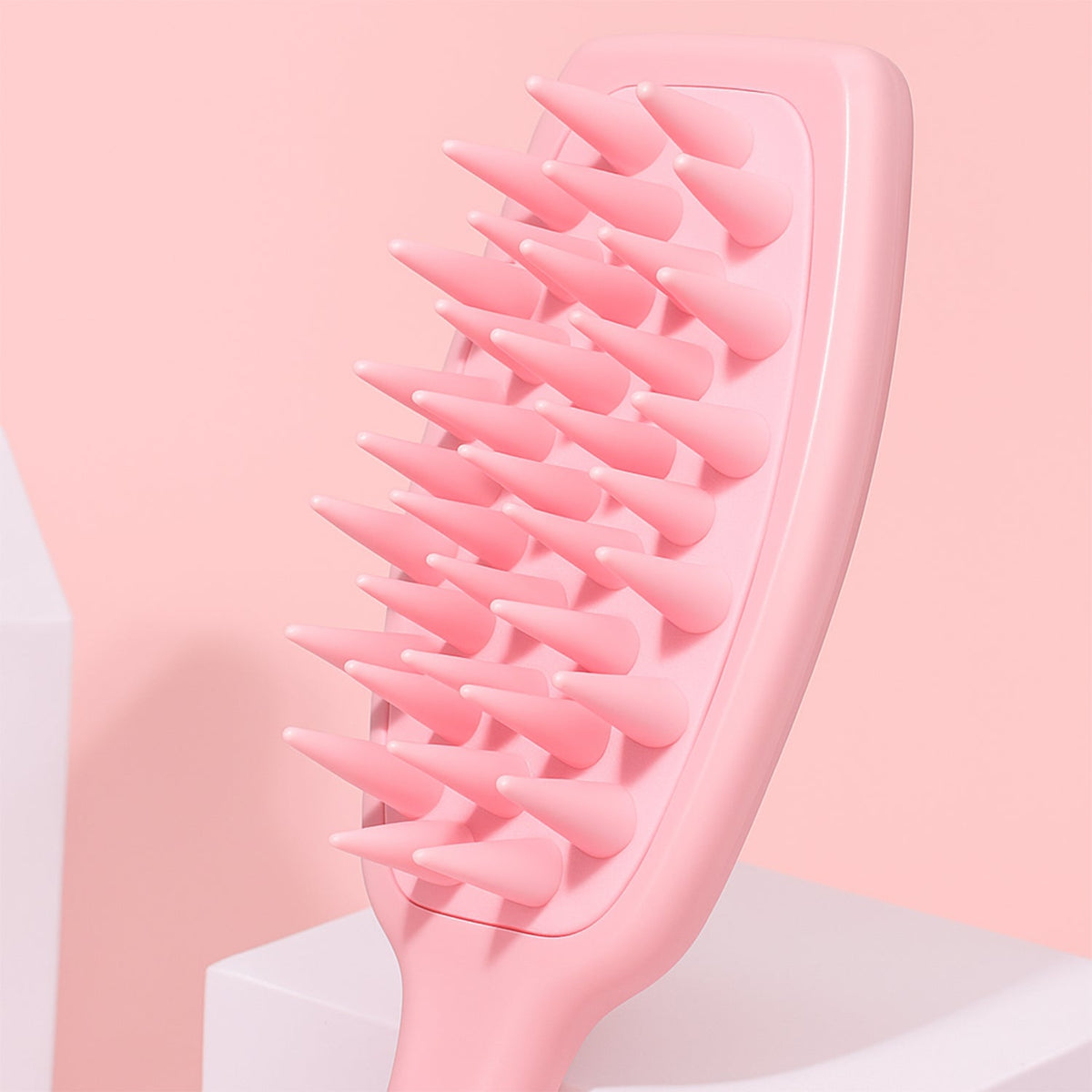 Close-up of the pink silicone scalp massager bristles on a pink and white background.