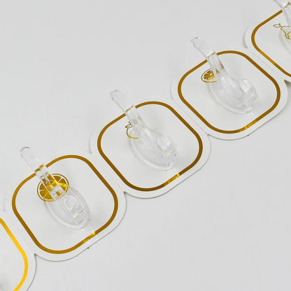 Close-up view of three transparent adhesive hooks with gold borders, showing the clear plastic hooks.