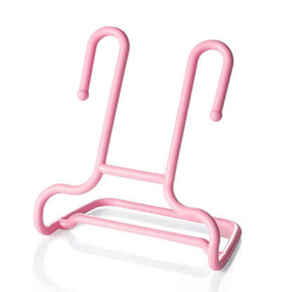 A single pink plastic shoe drying rack is shown on a reflective white surface.