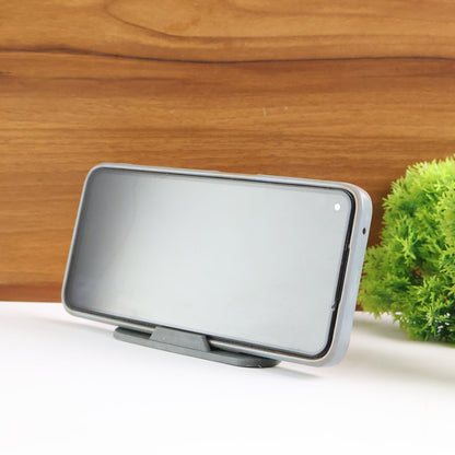 A smartphone rests horizontally on a black mobile stand, positioned on a white surface with a wooden background.