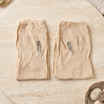 Two folded beige arm sleeves with "Let's Slim" logo, on a light marble surface with decorative items.
