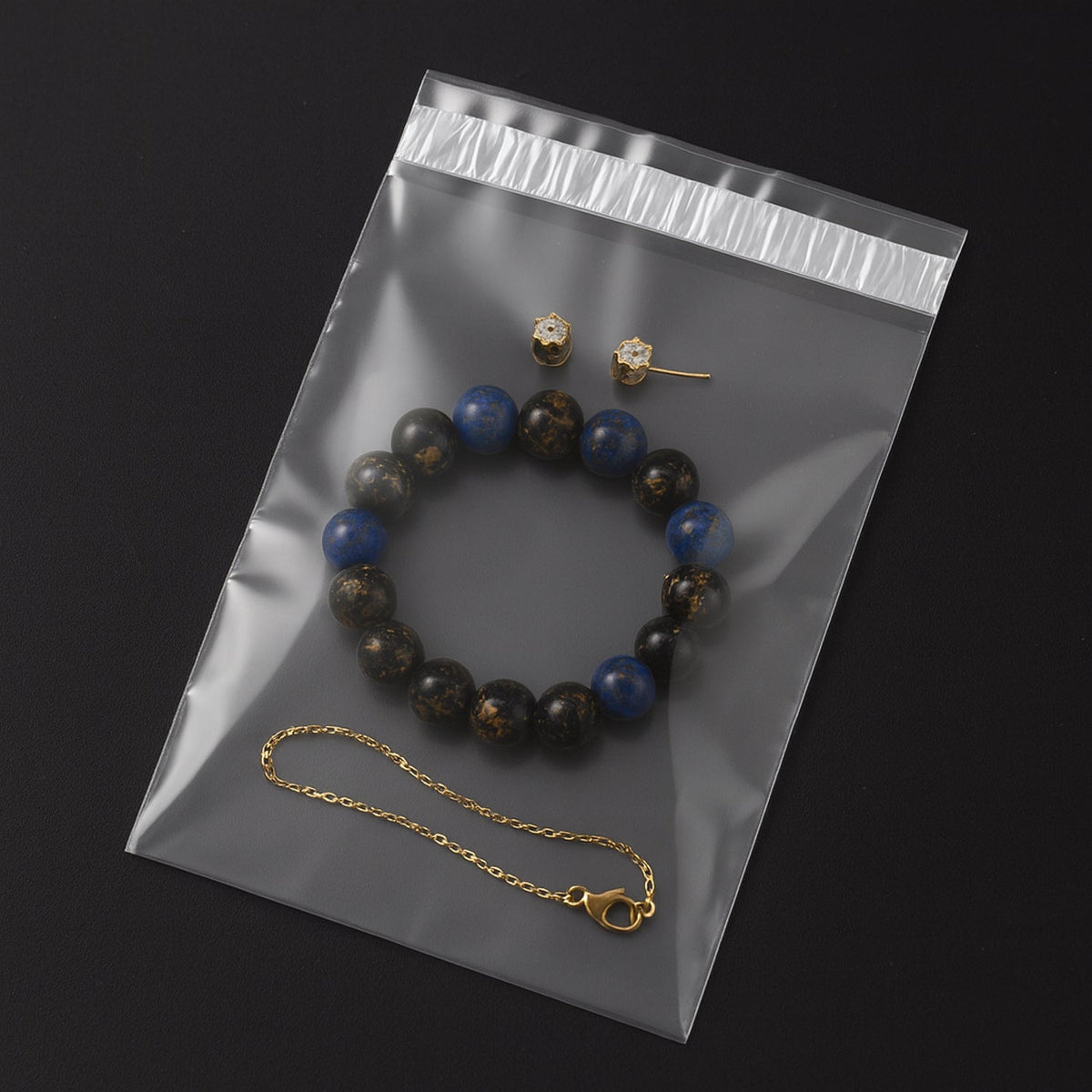 A clear polybag containing a beaded bracelet and small gold earrings on a dark background.