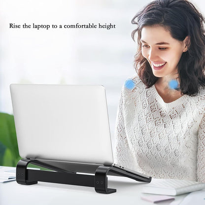 A woman smiles while working on a laptop elevated by a black stand on a white desk.