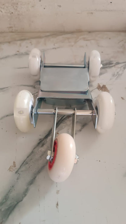 A silver metal roller stand with four white wheels and red accents is viewed from above on a marble surface.