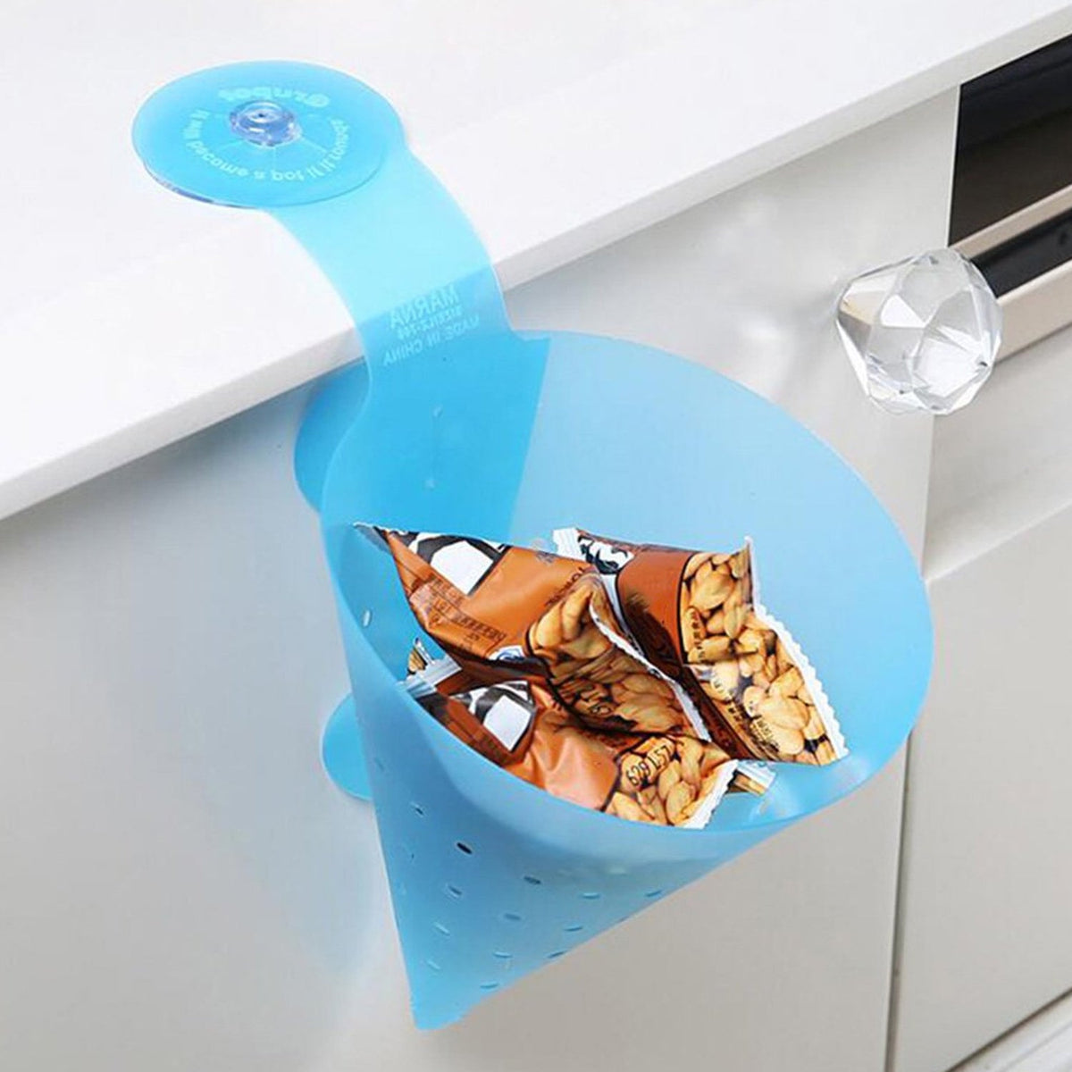 A blue silicone sink strainer with a suction cup, holding small snack bags, attached to a white cabinet.