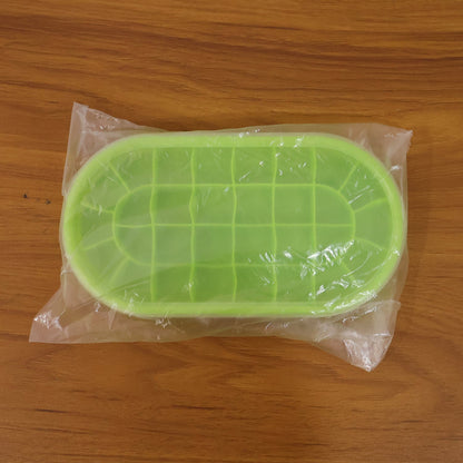 A green oval silicone ice cube tray sealed in clear plastic packaging, resting on a wooden surface.