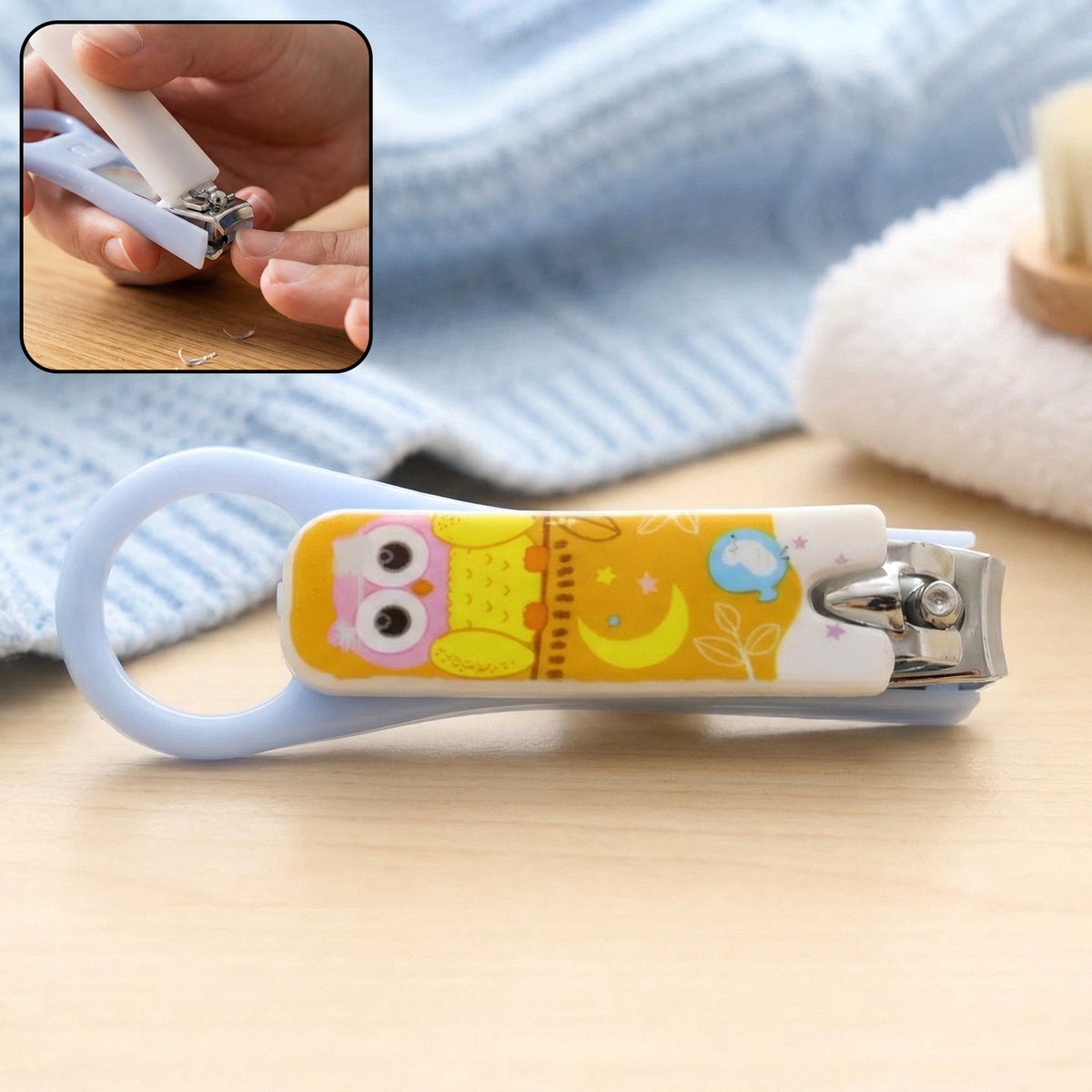 A light blue baby nail clipper with an owl design, with an inset showing it being used for nail trimming.