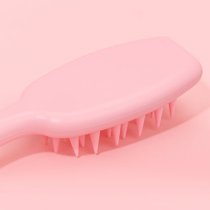 Close-up of the side profile of a pink silicone scalp massager brush on a pink background.