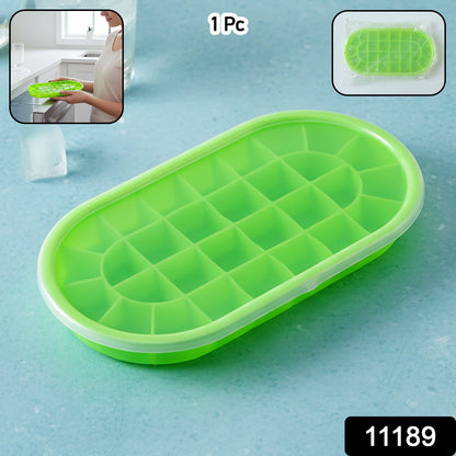 A green oval silicone ice cube tray with a clear lid, shown on a blue surface with ice cubes and a glass.