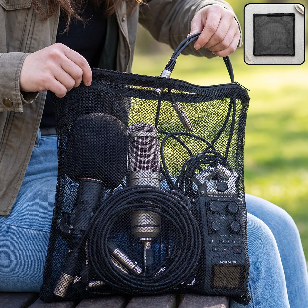 A person holds a black mesh zipper bag filled with microphones and audio cables outdoors.