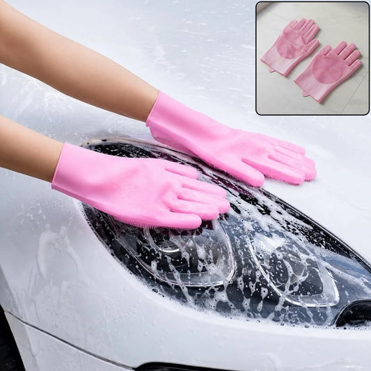 A person wearing pink silicone gloves with scrubbers on the palms and fingers, washing a white car with soap suds.