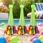 Three bunches of colorful self-tying water balloons with green nozzles, by a swimming pool on a sunny day.