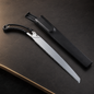 A silver and black folding pruning saw with a black sheath on a dark brown surface.
