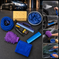 A car washing kit with a blue hose, purple mitt, yellow sponge, blue bucket, and various tools on a dark surface with a car