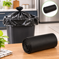 A black garbage bag tied in a knot inside a trash can, with a roll of bags on the table.