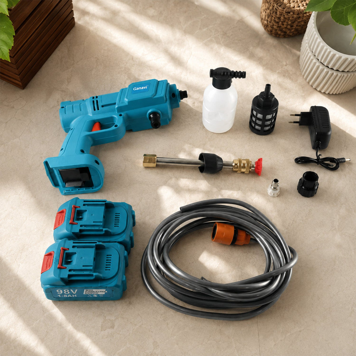 A teal wireless pressure washer with two batteries, a hose, various nozzles, a charger, and a soap dispenser on a