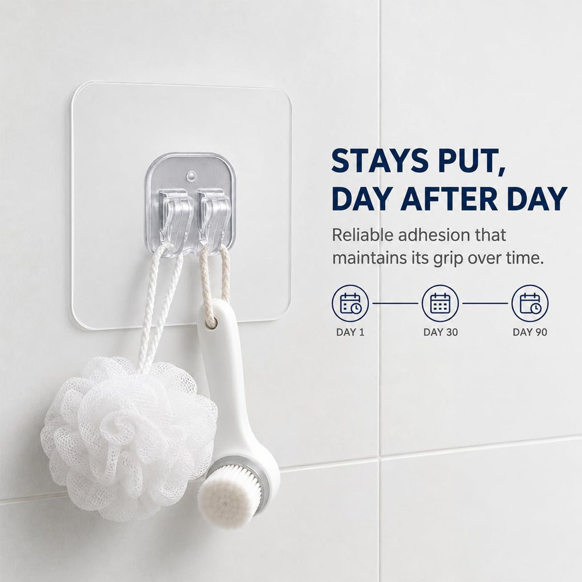 A white bath pouf and a white facial brush hang from a clear adhesive hook on a white tiled bathroom wall.