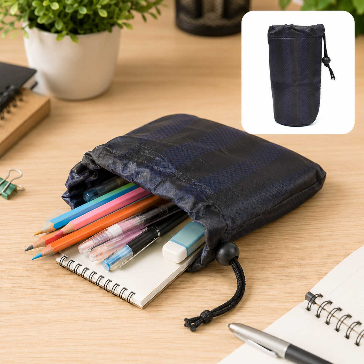 A navy blue drawstring pouch filled with colorful pencils, pens, and an eraser on a wooden desk. A smaller version of the