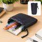 A navy blue drawstring pouch filled with colorful pencils, pens, and an eraser on a wooden desk. A smaller version of the