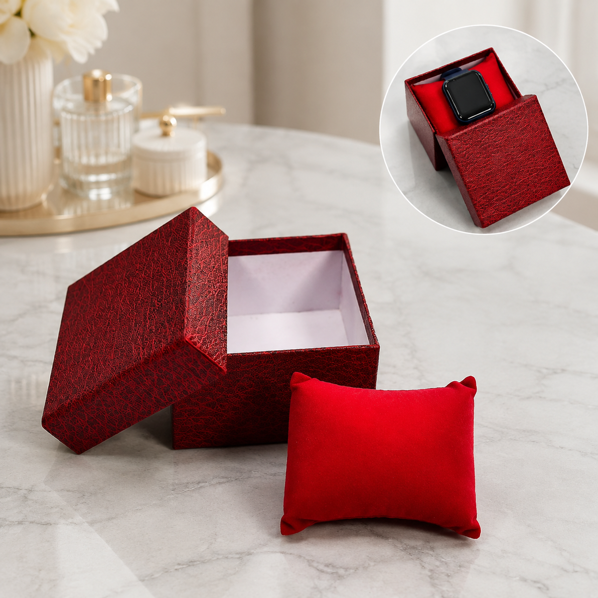 An open red textured gift box with a red velvet pillow on a marble surface, with a small inset showing a watch in the box.