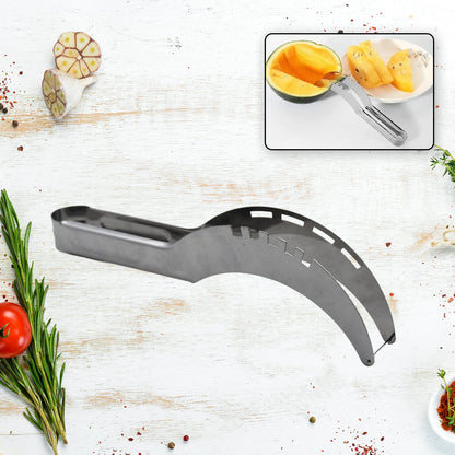 A silver stainless steel watermelon slicer lies on a white wooden surface with herbs and spices around it
