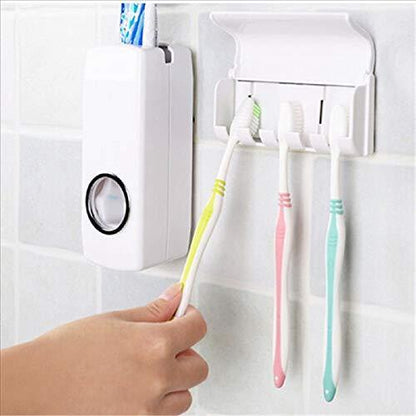 A hand holds a yellow toothbrush to the dispenser, with two other toothbrushes hanging in the holder.