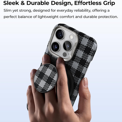 A hand holds a smartphone in a black and grey checkered case, with a matching checkered magnetic phone grip attached.