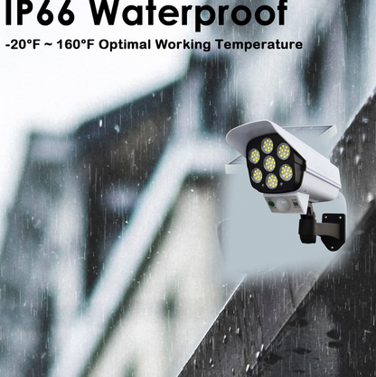 White dummy security camera with seven LED lights, shown against a blurred, rainy background, highlighting its waterproof
