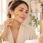 A woman in a white robe uses a yellow jade roller on her cheek, with a small inset showing the roller on a counter.