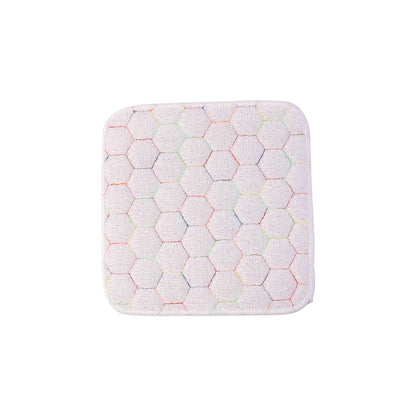 Close-up, top-down view of a white square cleaning cloth with a multicolored honeycomb pattern on a white background.