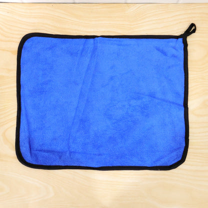 A blue microfiber cleaning cloth with a black border lies flat on a light wooden surface.