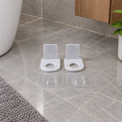 Two white plastic bottle holders with clear adhesive pads on a pure white background.
