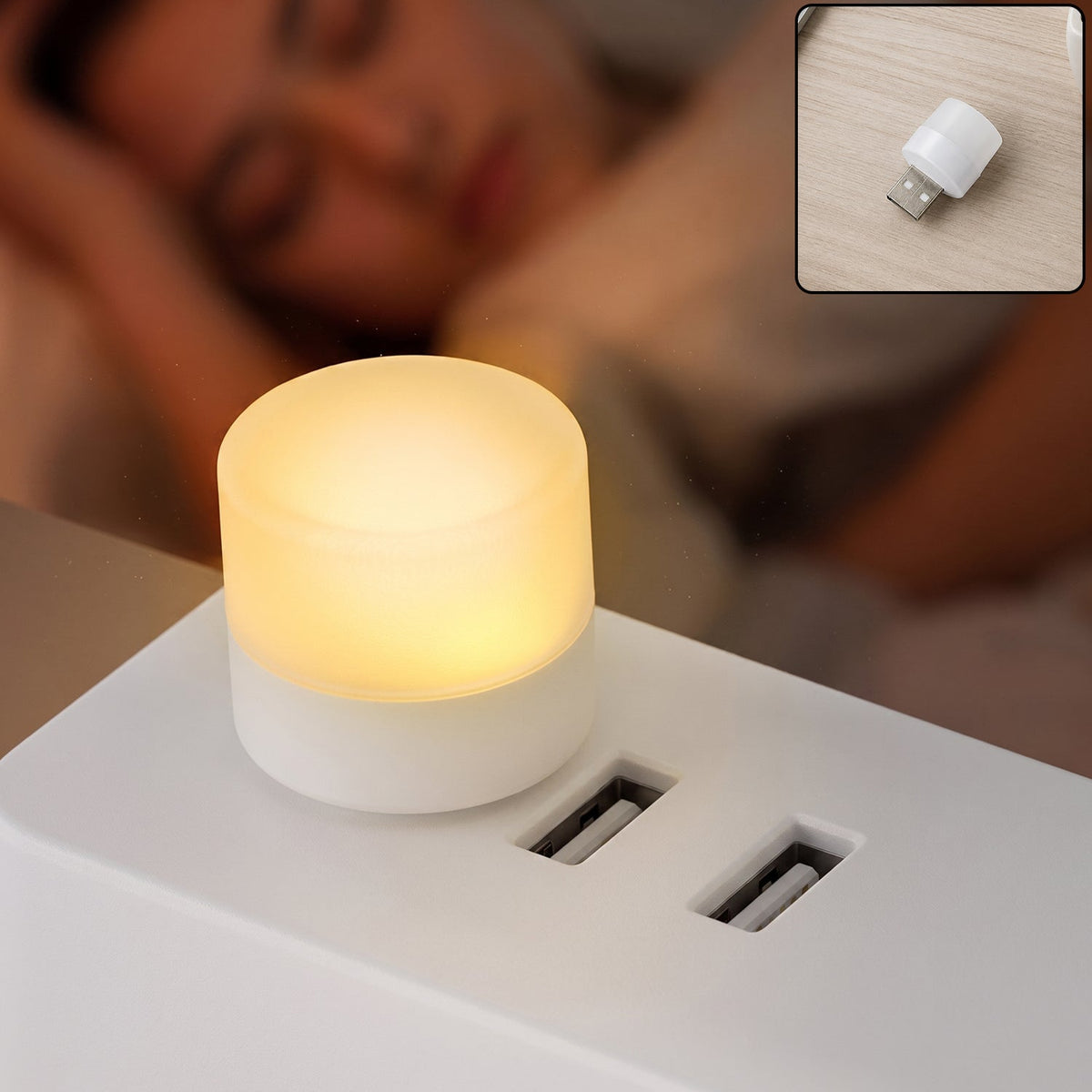 A small, glowing warm white USB night light plugged into a white power strip, with a sleeping person blurred in the