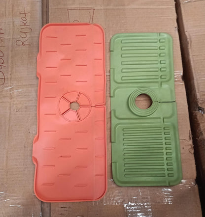 One orange and one green silicone faucet splash guard lying on a cardboard surface.