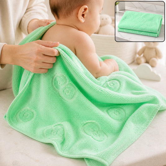 A baby is being dried with a light green microfiber towel featuring embossed heart and flower patterns.