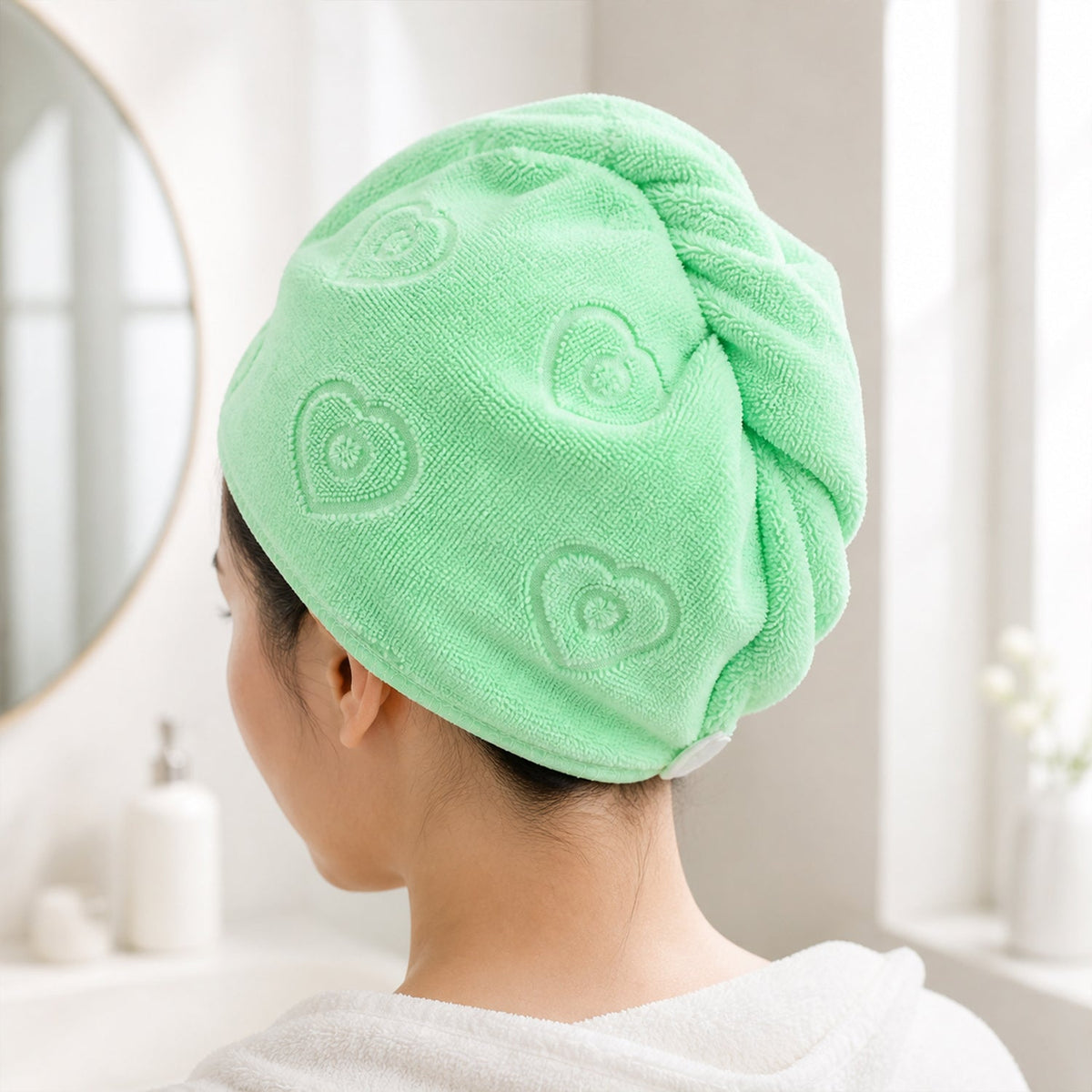A woman with her back to the camera, wearing a light green microfiber hair wrap with embossed patterns.