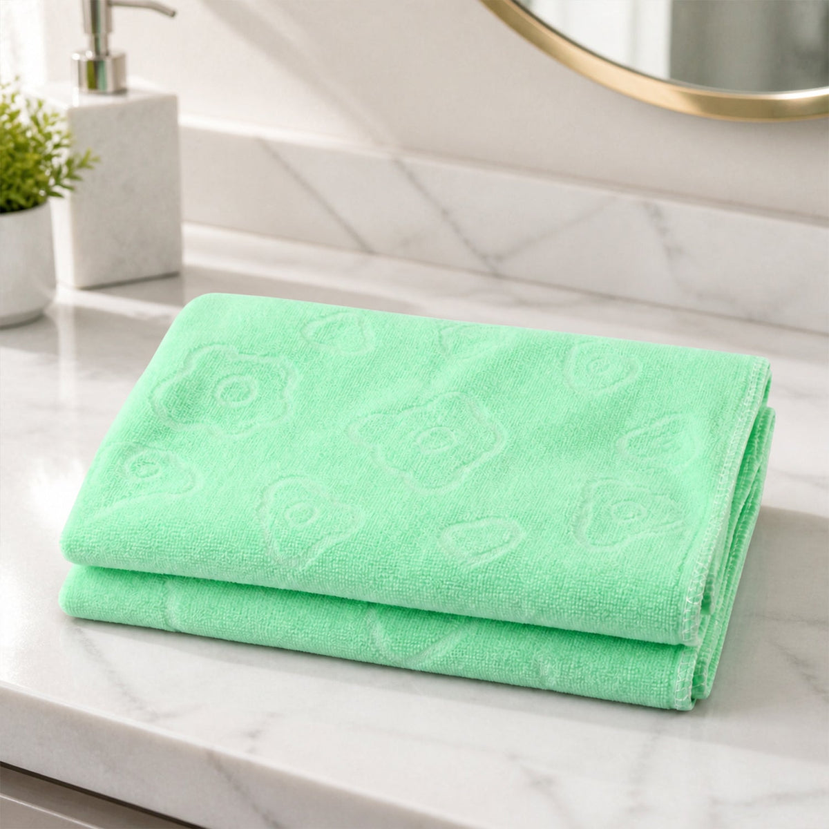 A folded light green microfiber towel with embossed patterns resting on a white marble bathroom counter.