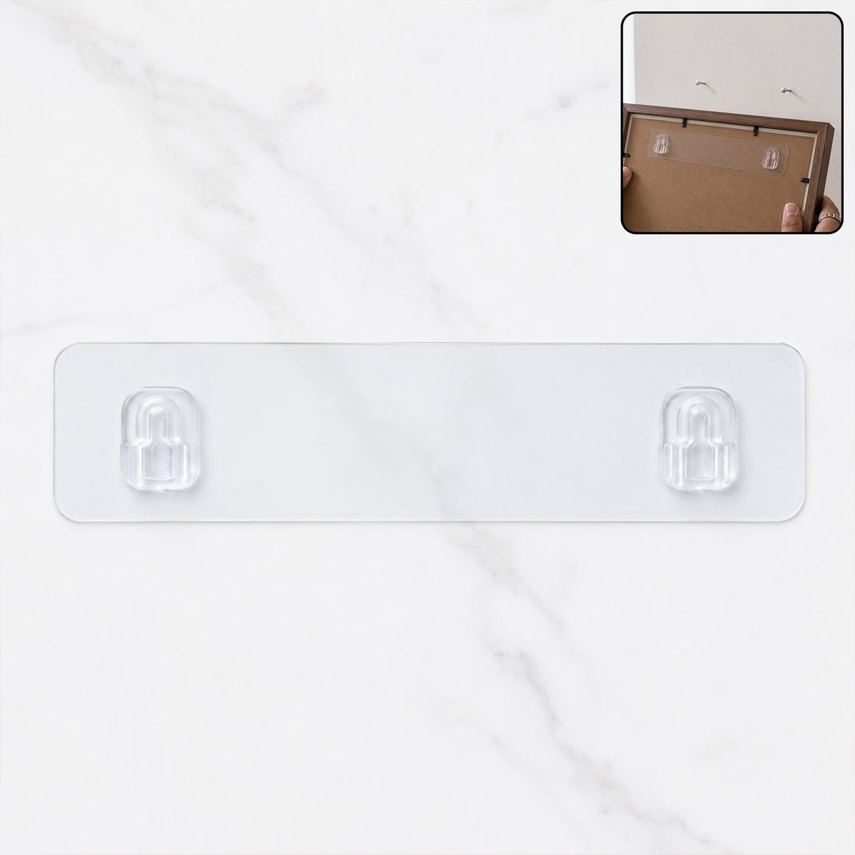 A clear adhesive wall hook strip with two hooks on a white marble background, with an inset showing it applied to a picture