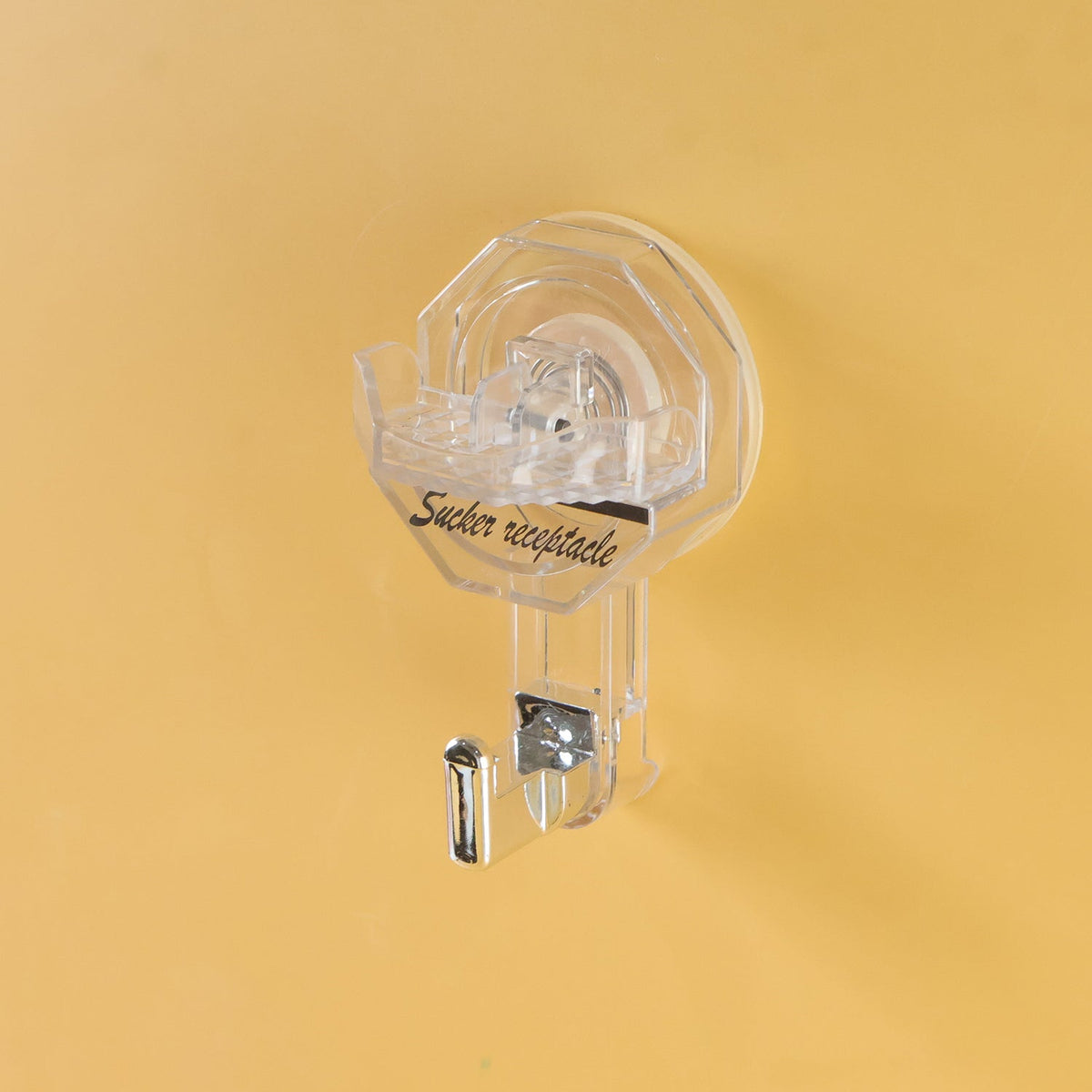 A clear, octagonal self-adhesive hook with a silver hook, attached to a plain yellow wall.