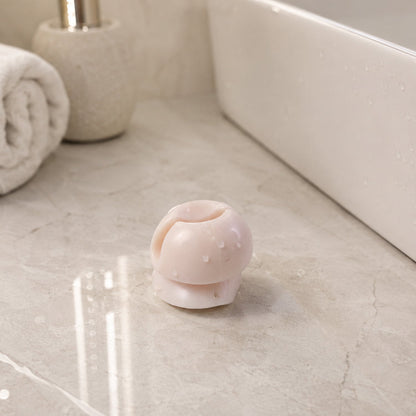 A single white toothbrush holder clip with water droplets on a light grey marble countertop next to a white sink and a