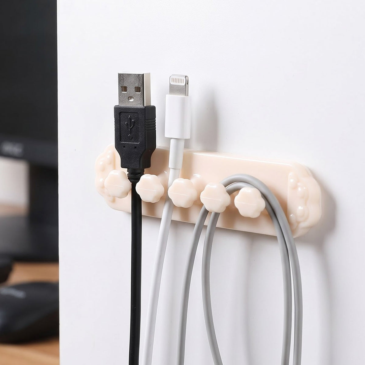A beige self-adhesive cable organizer clip with five flower-shaped holders, securing black, white, and gray USB – view 3