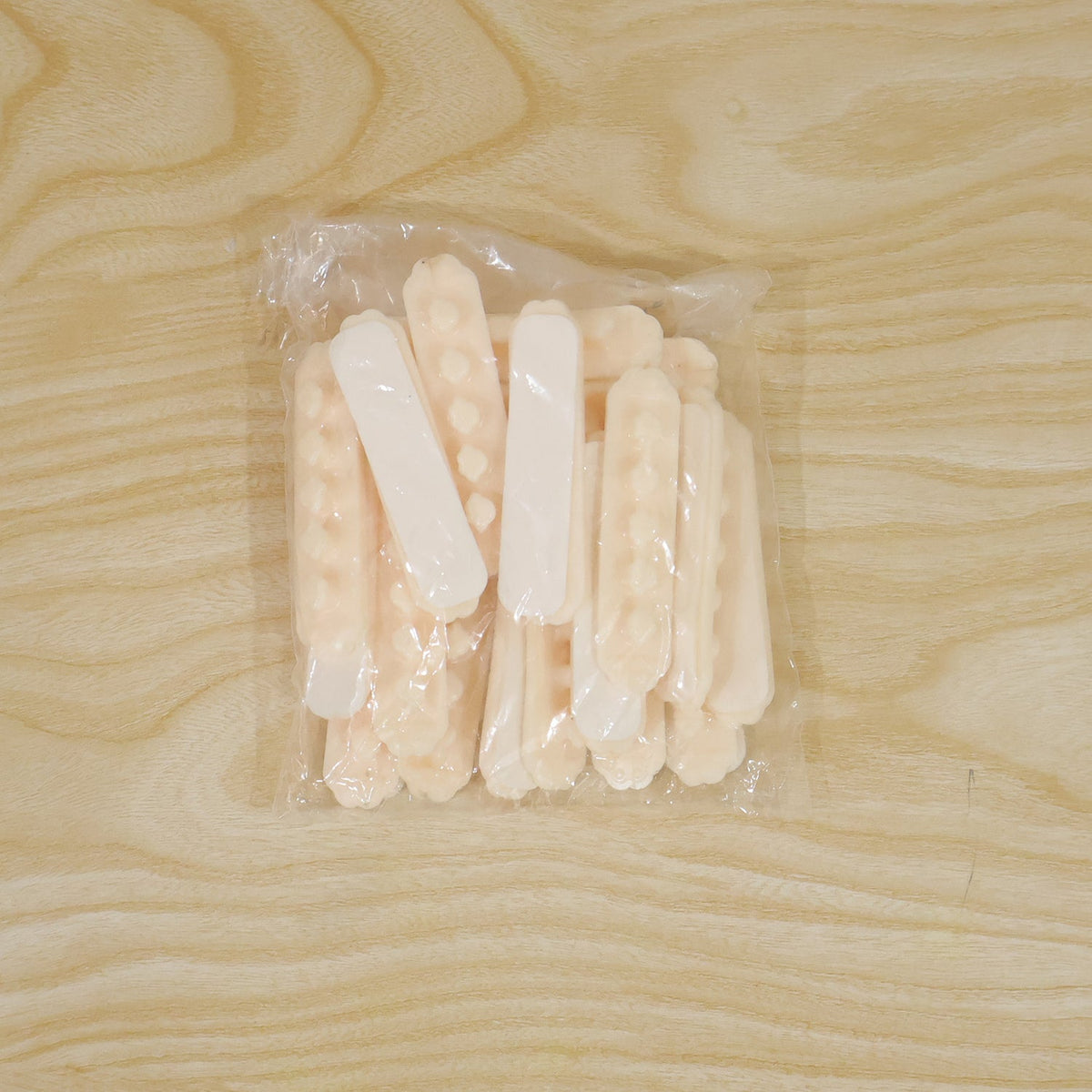 A clear plastic bag filled with multiple beige self-adhesive cable organizer clips, each with five flower-shaped holders, on