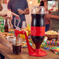 A person dispenses dark soda from an inverted bottle in a red plastic dispenser into a clear cup at a party.